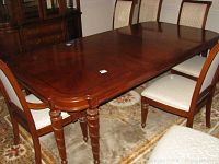 Full view of the polished wooden Stanley dining room table with elegant turned legs and chairs around it.