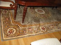 Corner and central section of the wool area rug showing floral medallion and detailed border pattern with warm earth tones.