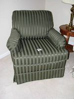 Front view of the green striped upholstered rocking chair showing cushioned arms and padded backrest.