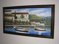 Full view of the framed painting showing boats on water with village and hills behind.