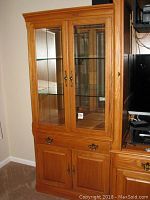 Full front view of the Thomasville cabinet showing two glass doors, brass handles, glass shelves, lower drawer, and cabinet doors.