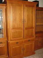 Front view of the Thomasville entertainment center showing two large upper doors, middle drawer, and lower cabinet doors with brass handles.