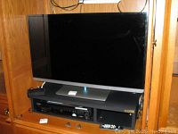 Toshiba 38 inch TV and Sony DVD player shown together in a cabinet with remote control visible.