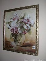 Full view of larger floral framed print with gold ornate frame showing flowers in a vase on a neutral background.