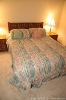 Full bed with wood headboard, bedding, pillows, and nightstands with lamps