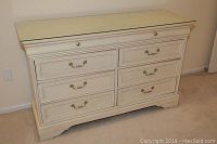 Full view of white Lexington Furniture dresser with glass top, eight drawers, brass handles, and shaped base.