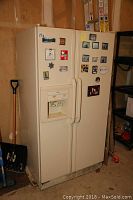 Front view of Whirlpool side-by-side refrigerator with magnets and photos on door, located in garage next to ladders and garden tools.