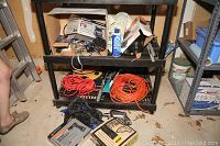 Tools arranged on shelving and floor in garage, showing cylinders and cords