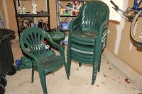 Eight green stackable plastic chairs stacked in garage space showing full lot