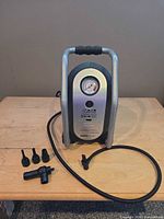 Front view of compressor with hose, power cord, gauge and five adapters