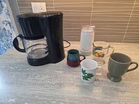 Coffee maker, grinder and all four mugs on countertop