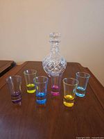 Crystal decanter and six coloured base liqueur glasses displayed