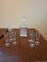 full set on wood surface: decanter center, six glasses surrounding