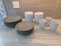 Stack of 6 dinner plates, 6 dessert plates, 8 bowls, 3 mugs on countertop