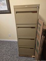 Front view of tan four-drawer metal filing cabinet