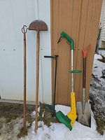 All six garden tools leaned against shed