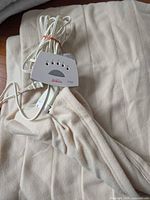 Folded cream electric blanket showing Sunbeam controller and cord