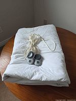 Folded white Sunbeam heated mattress pad with controllers on top