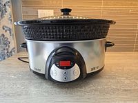 Front view of slow cooker showing stainless base, control panel, stoneware insert and lid