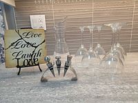 All items grouped: six wine glasses, decanter, three stoppers on holder, plaque on easel