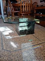 Coffee table showing glass top, green marble base and surrounding furniture for scale