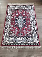 Full view of rug showing red field, cream border, fringe