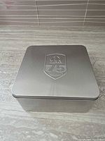 Closed silver tin showing embossed Mopar 75th logo