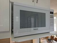 Front view of white Panasonic microwave showing Genius label and door window
