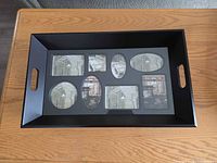 Top view of dark brown wooden serving tray showing glass insert with eight photo openings