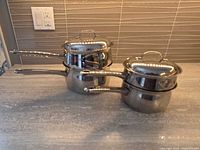 Side view of both saucepans with lids on