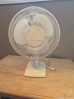Front view of white tabletop oscillating fan on wooden surface