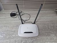 Router with antennas extended and power adapter on countertop