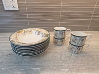 Stack of eight soup bowls and four cups displayed on countertop