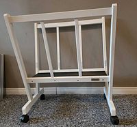 Front angle view of white wood artist storage rack showing frame, dividers and castors