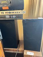 Front view of both speakers with grilles on; shows tear on right grille