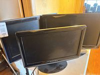 Front view showing three flat-panel screens, Dynex label visible on center unit