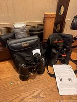 Overall view showing Bushnell binocular, Celestron binocular in bag, multiple cases and manual