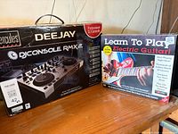 Front of boxed Hercules DJConsole RMX2 and Learn To Play Electric Guitar kit on shelf
