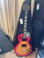 Full view of Gibson Les Paul Studio Lite guitar leaning against gig bag