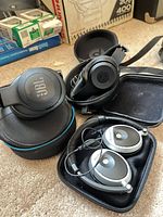 Three pairs of headphones in cases: JBL, Beats, Bose