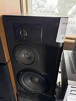 Front view of JBL speaker with grille removed showing tweeter marked Pure Titanium, midrange and woofer