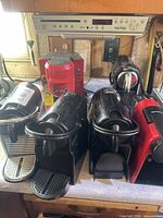 Front view showing four Nespresso machines and one red Keurig brewer behind