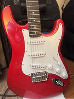Front body view showing red finish, white pickguard, pickups, controls, bridge