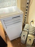 Danby air conditioner front with two oil-filled heaters beside it