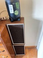 Stacked view of two matching speakers beside furniture