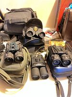 Four binoculars with three cases displayed on table