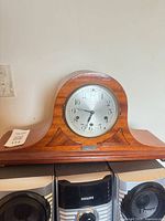 Front view of wooden tambour clock on shelf