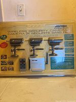 Sealed retail package showing three cameras, receiver and remote