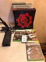 Black Xbox 360 S Gears of War console, white console stacked, power supply, three game cases visible