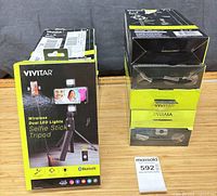 Front view of boxed Vivitar selfie stick tripod and additional boxed units stacked